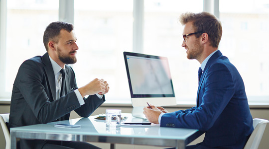 2 guys discussing business at desk